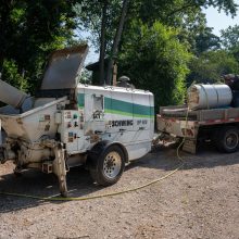 A concrete mixer truck loading concrete into a mixing bucket.