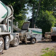 A concrete mixer truck loading concrete into a mixing bucket.